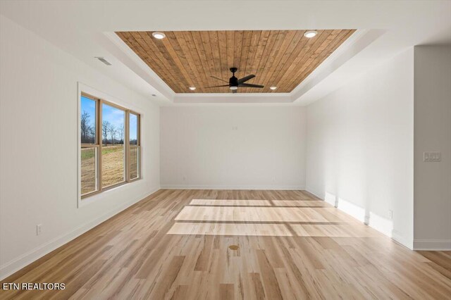 unfurnished room with a tray ceiling, light hardwood / wood-style flooring, ceiling fan, and wooden ceiling