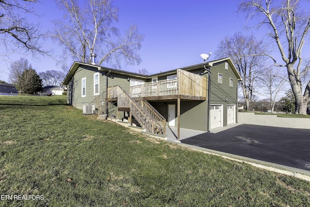 back of property featuring a garage, a wooden deck, cooling unit, and a yard