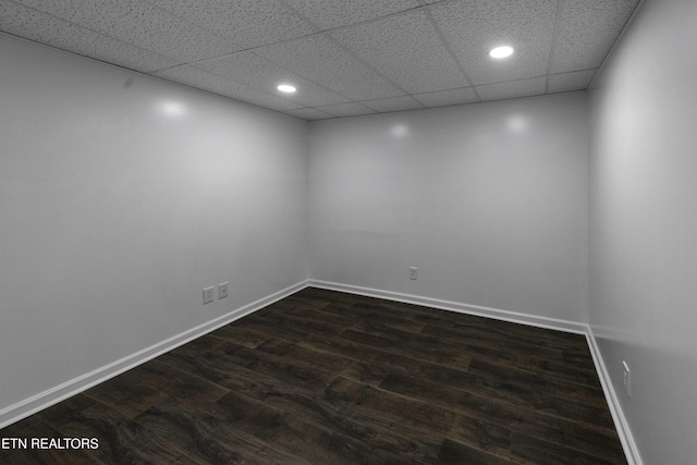 spare room featuring a paneled ceiling and dark wood-type flooring