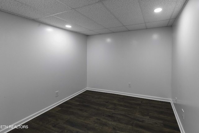 spare room with a drop ceiling and dark hardwood / wood-style flooring