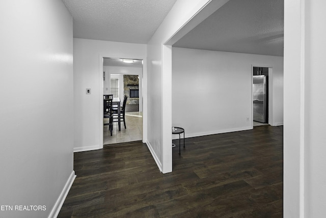 hall with a textured ceiling and dark wood-type flooring