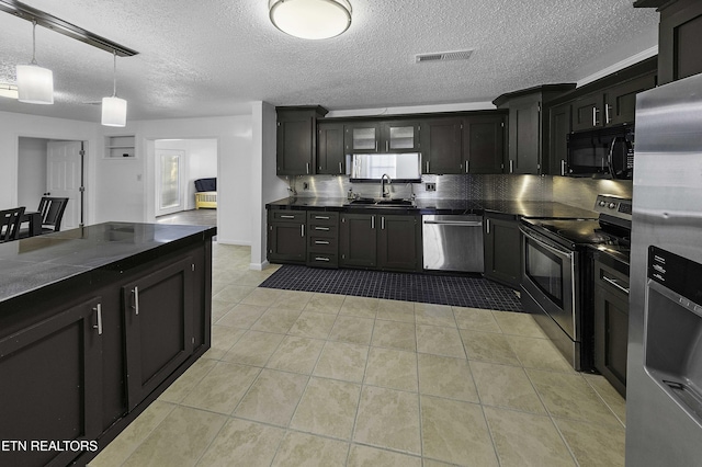 kitchen featuring decorative light fixtures, sink, stainless steel appliances, a textured ceiling, and light tile patterned floors