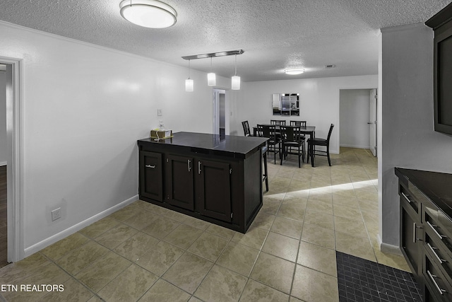 kitchen with hanging light fixtures, light tile patterned floors, and a textured ceiling