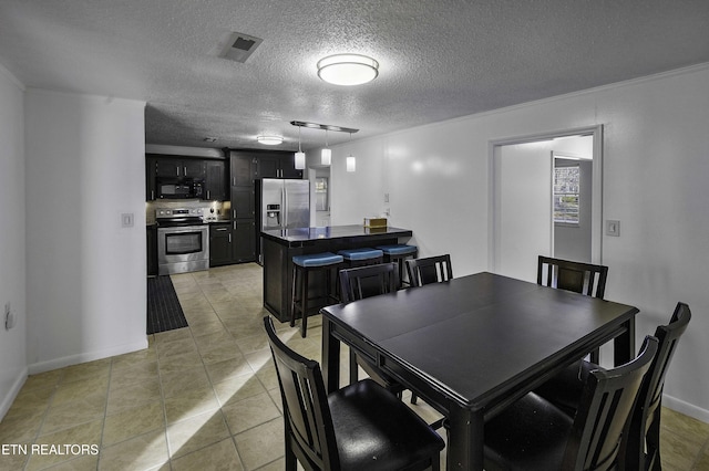 dining area featuring a textured ceiling, light tile patterned floors, and ornamental molding