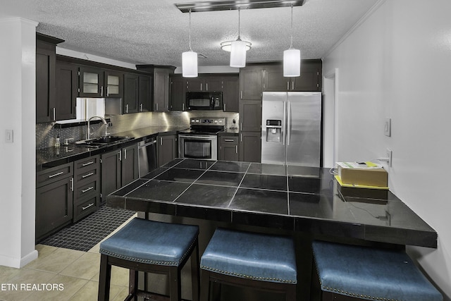 kitchen with pendant lighting, kitchen peninsula, sink, a kitchen breakfast bar, and stainless steel appliances