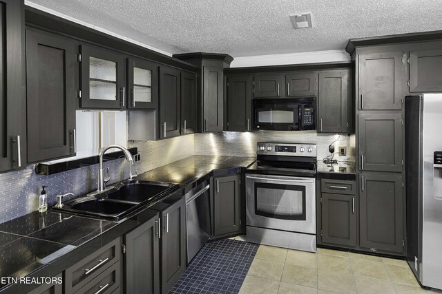 kitchen featuring appliances with stainless steel finishes, decorative backsplash, light tile patterned flooring, a textured ceiling, and sink