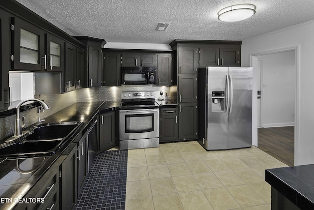 kitchen with a textured ceiling, stainless steel appliances, sink, ornamental molding, and light tile patterned floors