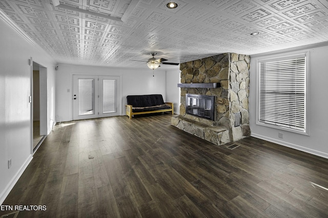 unfurnished living room featuring ceiling fan, dark wood-type flooring, and a stone fireplace