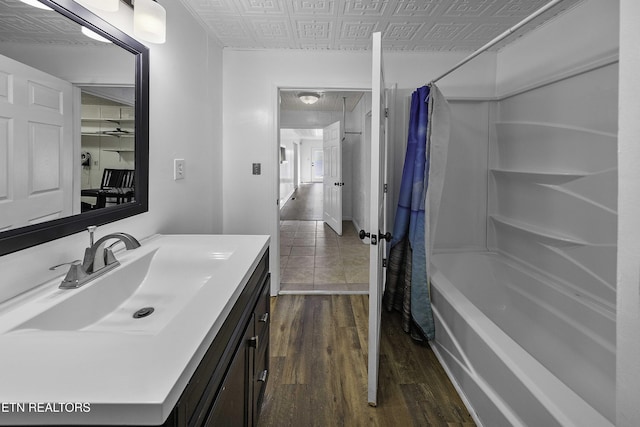 bathroom featuring hardwood / wood-style floors, vanity, and shower / bathtub combination with curtain