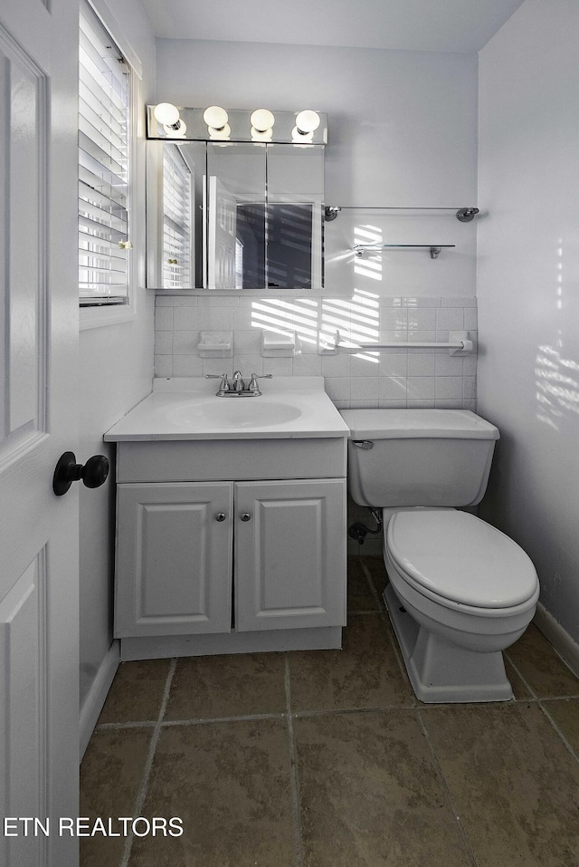 bathroom featuring toilet, tile walls, and vanity