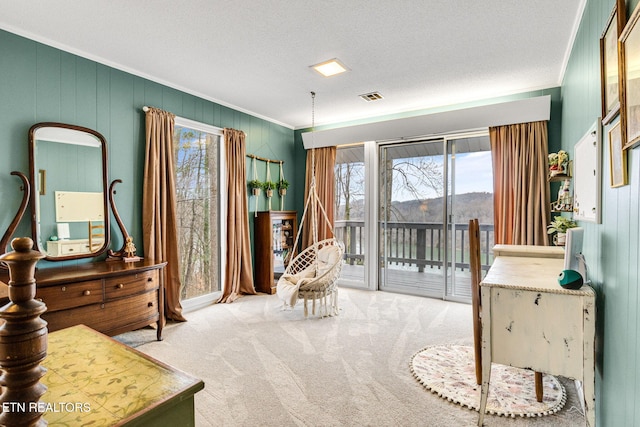 sitting room featuring carpet floors, a wealth of natural light, a textured ceiling, and ornamental molding