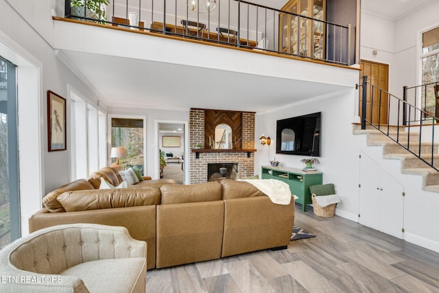 living room featuring hardwood / wood-style floors, ornamental molding, a fireplace, and plenty of natural light