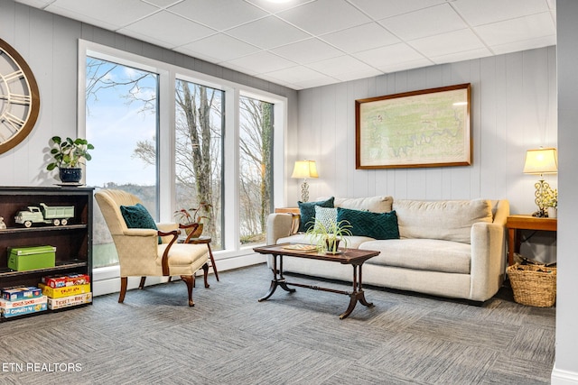 carpeted living room featuring wood walls