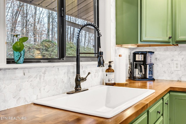 kitchen with tasteful backsplash, butcher block countertops, sink, and green cabinets