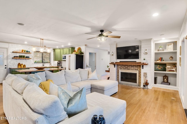 living room featuring a brick fireplace, light hardwood / wood-style flooring, and ceiling fan