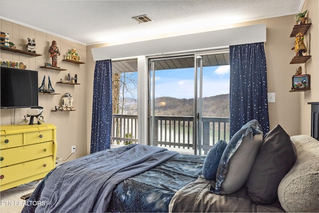 bedroom with access to exterior, a textured ceiling, ornamental molding, and a water view