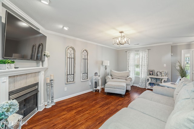 living room with dark hardwood / wood-style floors, a tiled fireplace, crown molding, and an inviting chandelier