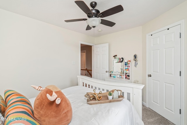 bedroom featuring carpet, ceiling fan, and a crib