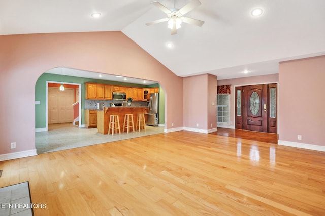 unfurnished living room featuring light hardwood / wood-style flooring, high vaulted ceiling, and ceiling fan