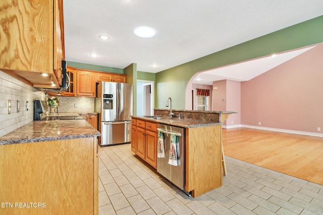 kitchen featuring sink, a breakfast bar area, appliances with stainless steel finishes, a kitchen island with sink, and tasteful backsplash