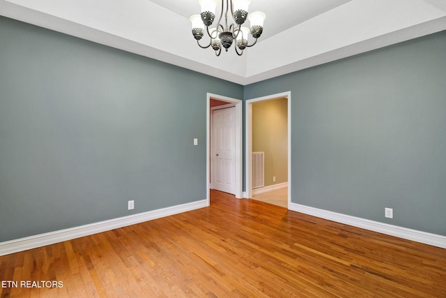 unfurnished room featuring hardwood / wood-style floors and a chandelier