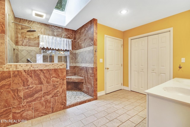 bathroom with vanity, a skylight, and a tile shower