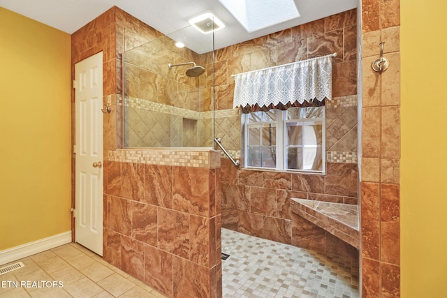 bathroom featuring a tile shower, tile patterned floors, and a skylight