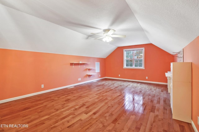 bonus room with ceiling fan, wood-type flooring, a textured ceiling, and vaulted ceiling