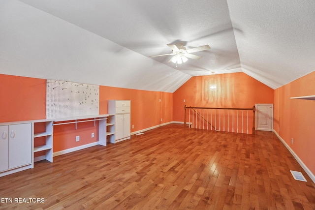 additional living space featuring ceiling fan, lofted ceiling, hardwood / wood-style floors, and a textured ceiling