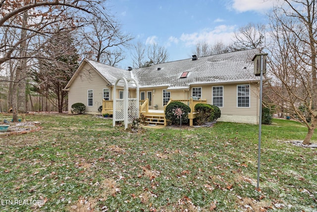 rear view of property featuring a wooden deck and a lawn