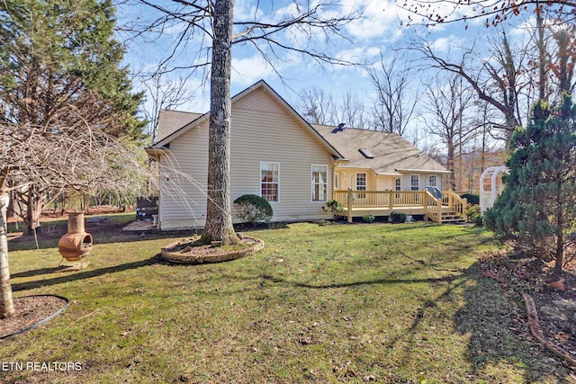 back of property featuring a wooden deck and a lawn