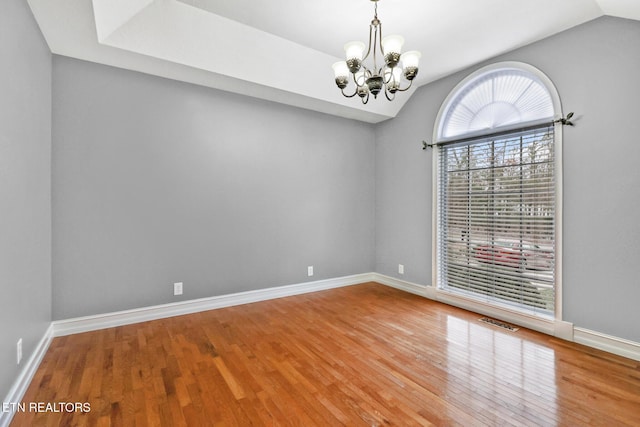 unfurnished room featuring hardwood / wood-style flooring, lofted ceiling, and a notable chandelier