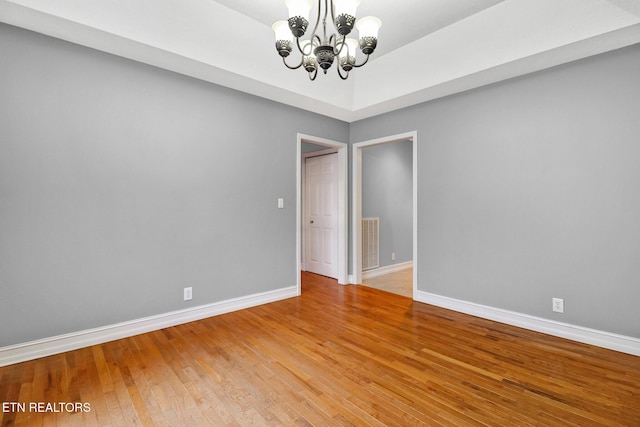 spare room with hardwood / wood-style floors and a notable chandelier