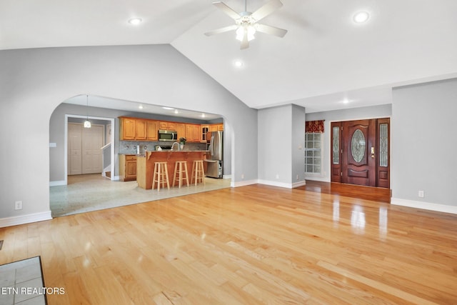 unfurnished living room with ceiling fan, high vaulted ceiling, and light wood-type flooring