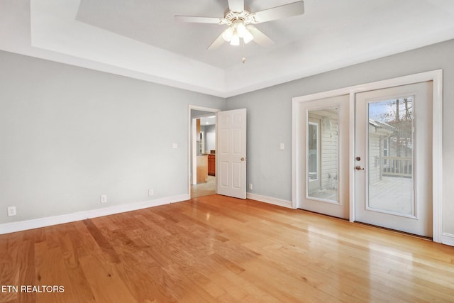 spare room featuring light hardwood / wood-style flooring, a raised ceiling, and ceiling fan