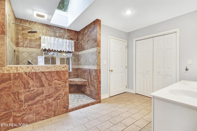 bathroom featuring vanity, a wealth of natural light, a skylight, and tiled shower