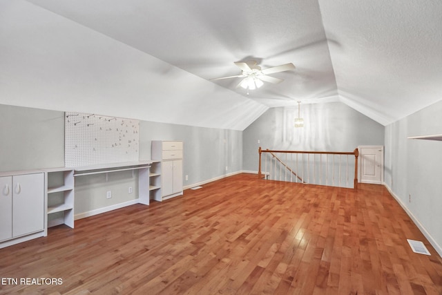 bonus room featuring hardwood / wood-style flooring, lofted ceiling, a textured ceiling, and ceiling fan