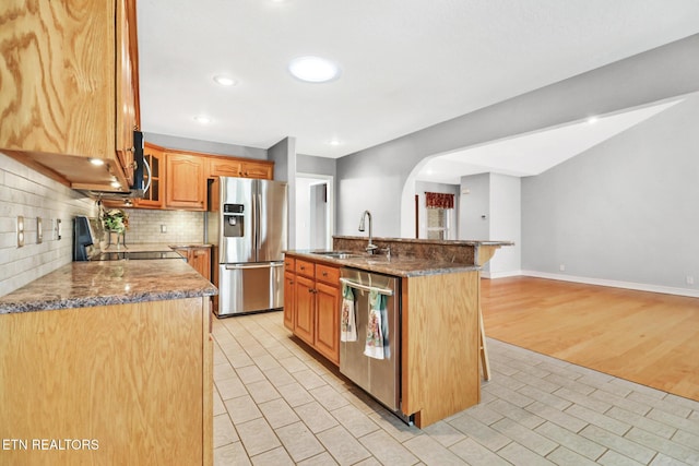 kitchen with sink, a breakfast bar area, tasteful backsplash, appliances with stainless steel finishes, and an island with sink