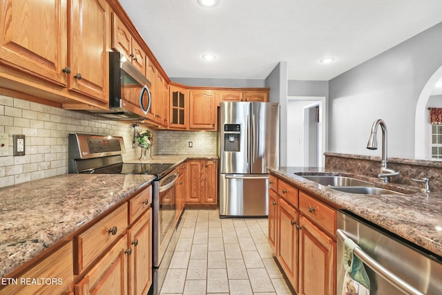 kitchen featuring sink, light stone counters, tasteful backsplash, light tile patterned floors, and stainless steel appliances