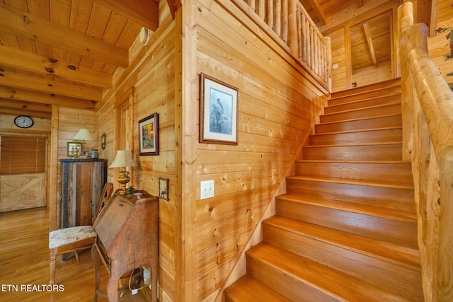 stairs featuring beamed ceiling, wooden ceiling, and wood walls