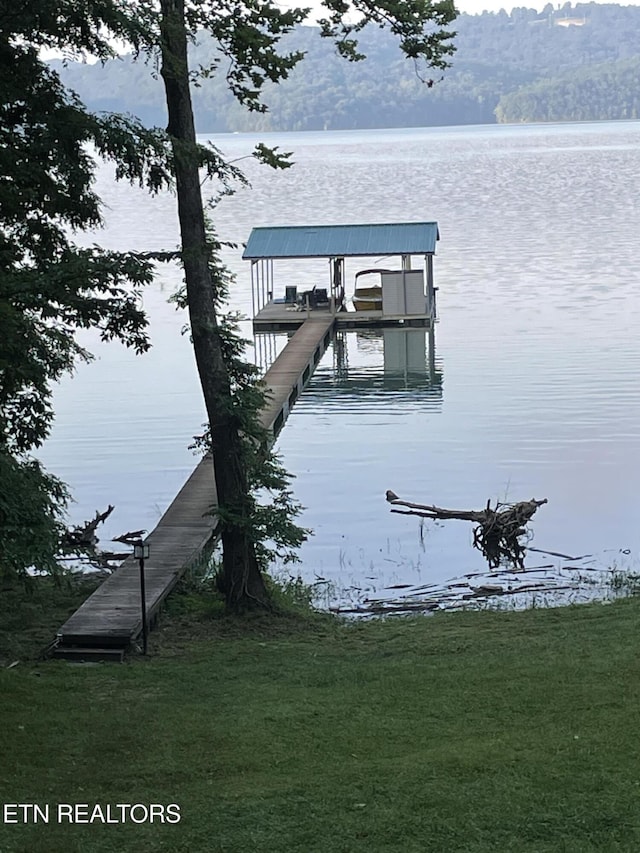 view of dock featuring a lawn and a water view