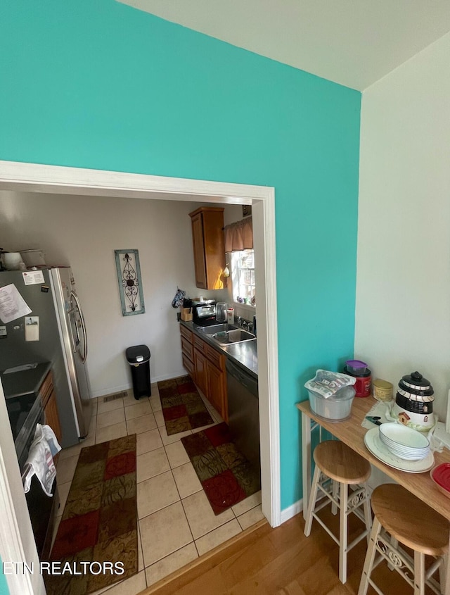 kitchen featuring stainless steel fridge with ice dispenser, dishwasher, light tile patterned flooring, and sink