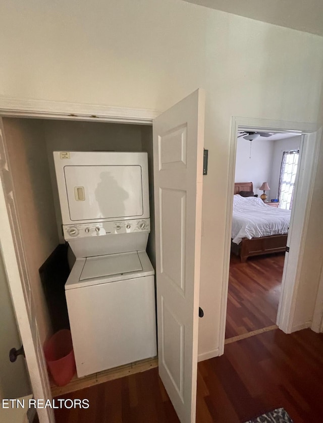 clothes washing area with dark hardwood / wood-style flooring and stacked washer and clothes dryer