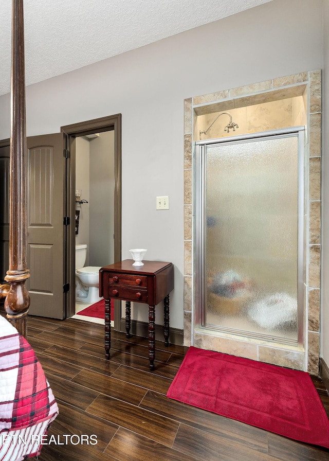 bathroom featuring a textured ceiling, toilet, and walk in shower