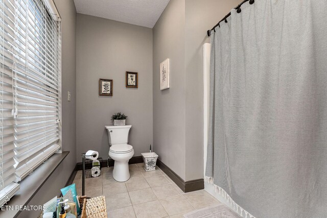 bathroom with tile patterned flooring, toilet, and a textured ceiling