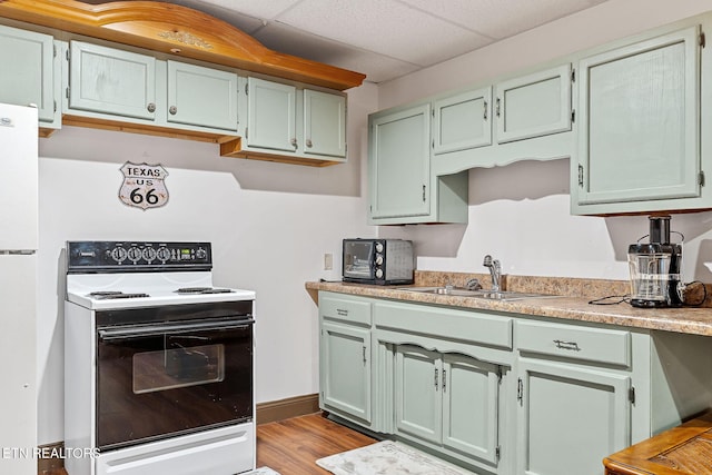 kitchen with white appliances, light hardwood / wood-style floors, a paneled ceiling, and sink