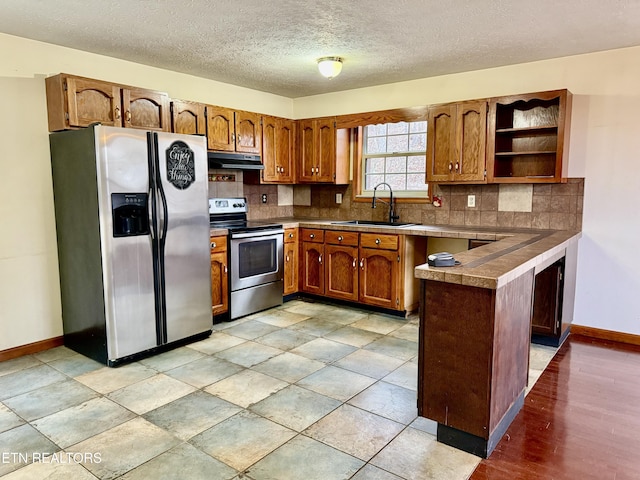 kitchen featuring sink, stainless steel appliances, backsplash, kitchen peninsula, and a textured ceiling