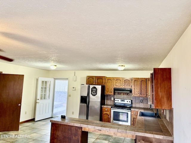 kitchen with sink, tasteful backsplash, range hood, kitchen peninsula, and appliances with stainless steel finishes