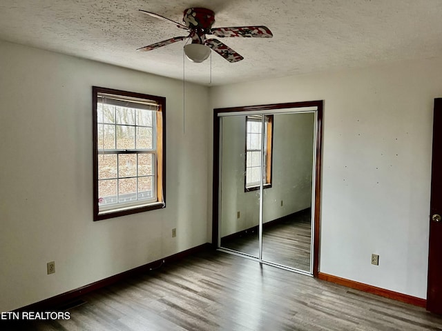 unfurnished bedroom featuring ceiling fan, a closet, wood-type flooring, and a textured ceiling