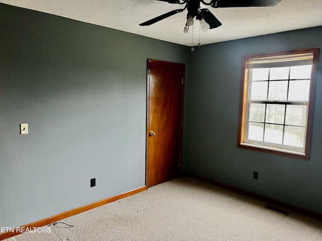 spare room with ceiling fan, light colored carpet, and a textured ceiling